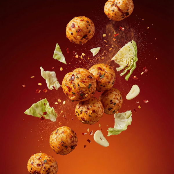 Floating kimchi flavoured makhana showing its crunchy texture and reddish seasoning against a soft background